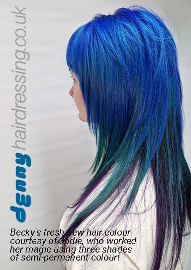 A woman with long hair in shades of blue and green presents a bold and colorful hairstyle.